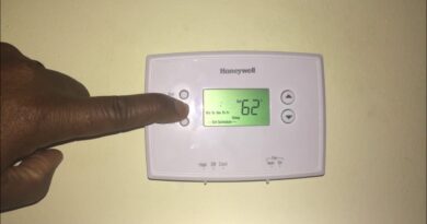 A close up of a person programming a digital Honeywell thermostat on a wall