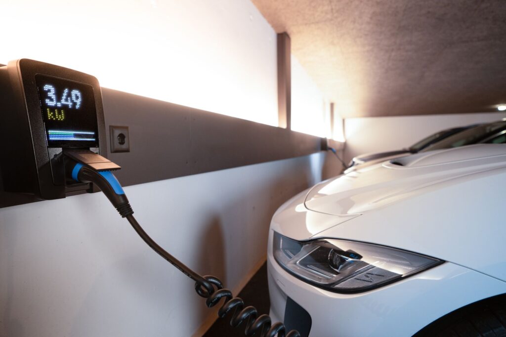 An electric vehicle plugged into a wall charger inside a modern residential garage